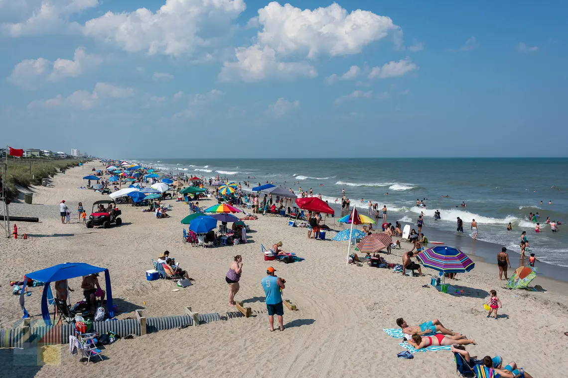 Beach goers next to Kure Beach Pier